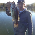 Fisherman holds largemouth bass from ball pond